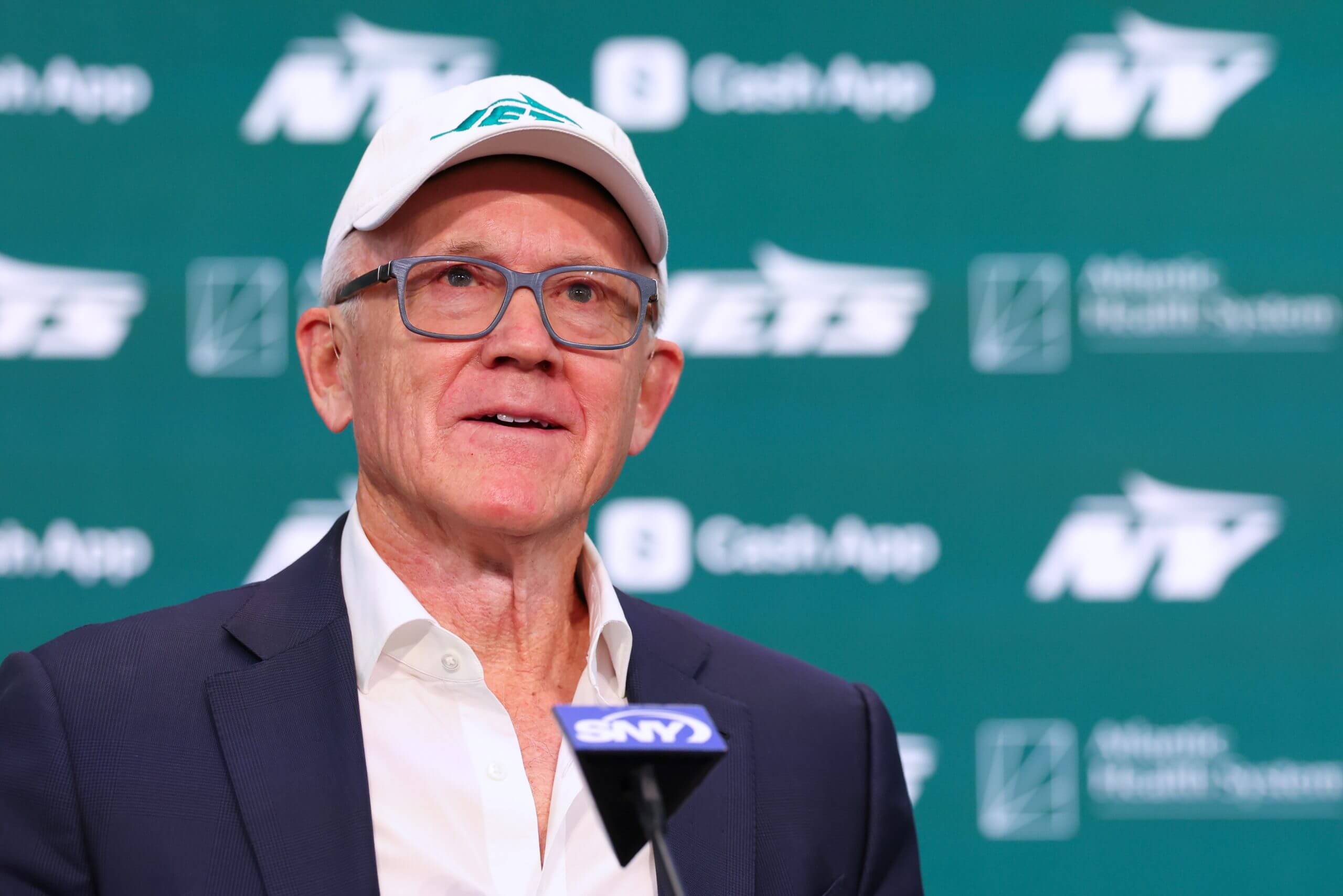 Jets owner Woody Johnson announces new head coach Aaron Glenn and GM Darren Mougey at a 2025 press conference.